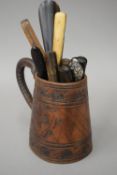 A collection of 18th/19th century cutlery with horn forks etc, in a leather tankard.