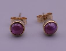 A pair of 9 ct gold and ruby cabochon set earrings. 5 mm diameter.