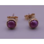 A pair of 9 ct gold and ruby cabochon set earrings. 5 mm diameter.