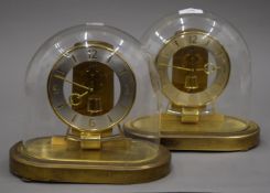 Two Kundo electronic clocks under glass domes. Each 22 cm high.