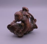 A wooden netsuke formed as a boy and fish. 4.5 cm x 4 cm.