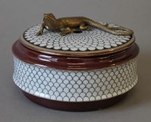 A porcelain box surmounted with a lizard. 14 cm diameter.