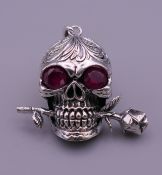 A silver skull form pendant. 2 cm high.