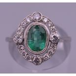 A platinum emerald and diamond ring. Ring size N.