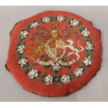 A beadwork armorial cushion. 32 cm diameter.