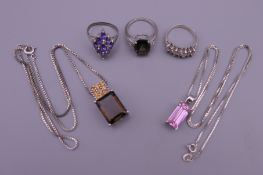 Three silver ladies rings and two silver pendants on silver chains.