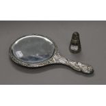 A silver cherub hand mirror and a silver pepper pot.