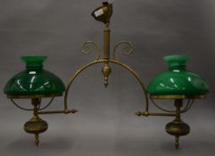 A brass hanging light with two green glass shades.