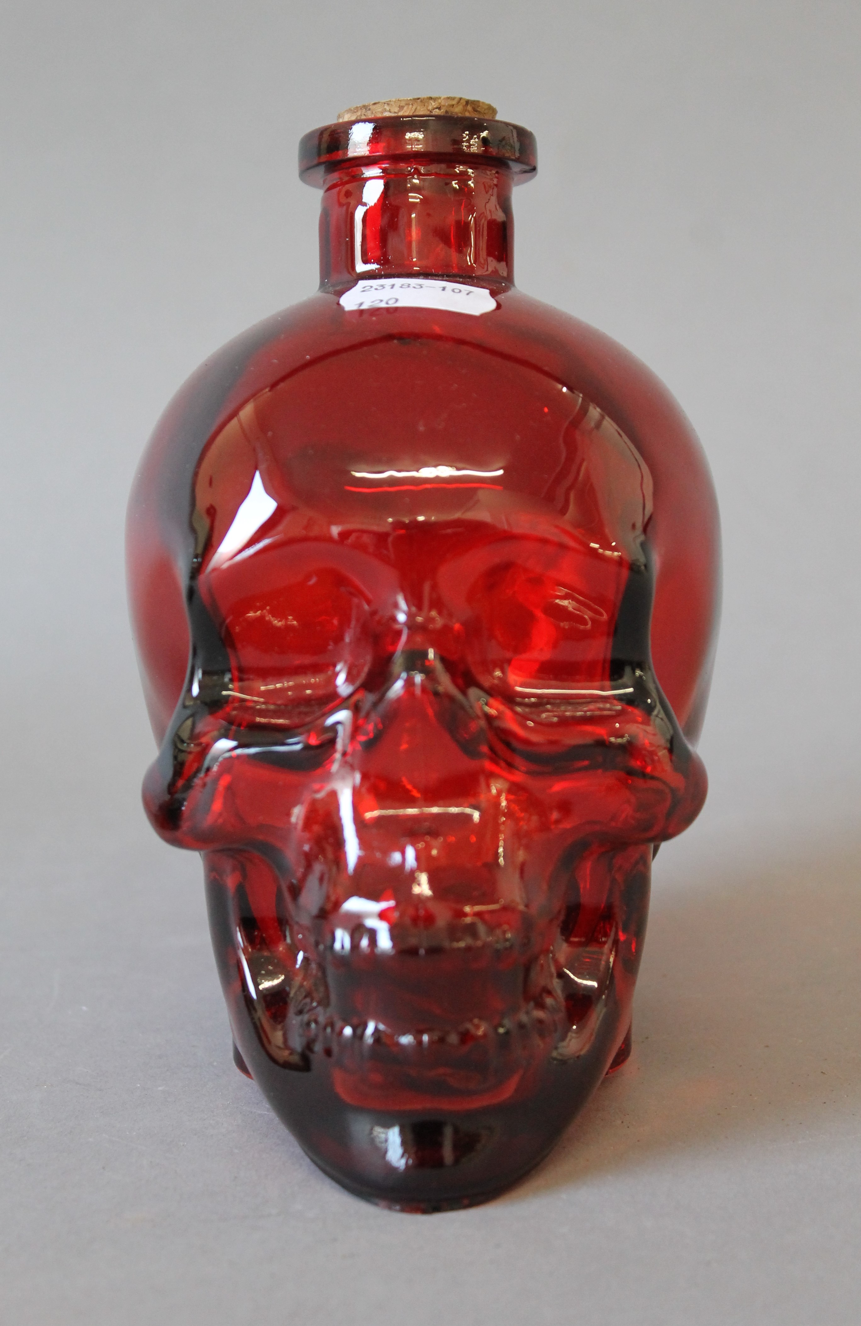 A red glass skull form decanter. 15 cm high.
