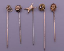 Five gold and diamond stick pins. Largest 6 cm high. 6 grammes total weight.