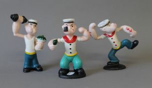 A set of three cast iron Popeye figures. The largest 16 cm high.