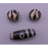 Three Tibetan dzi beads. Largest 3.25 cm long.