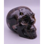 A tigers eye type stone model of a skull. 7 cm high x 9.5 cm long.