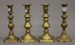 Four 19th century brass ejector candlesticks. Each approximately 20 cm high.