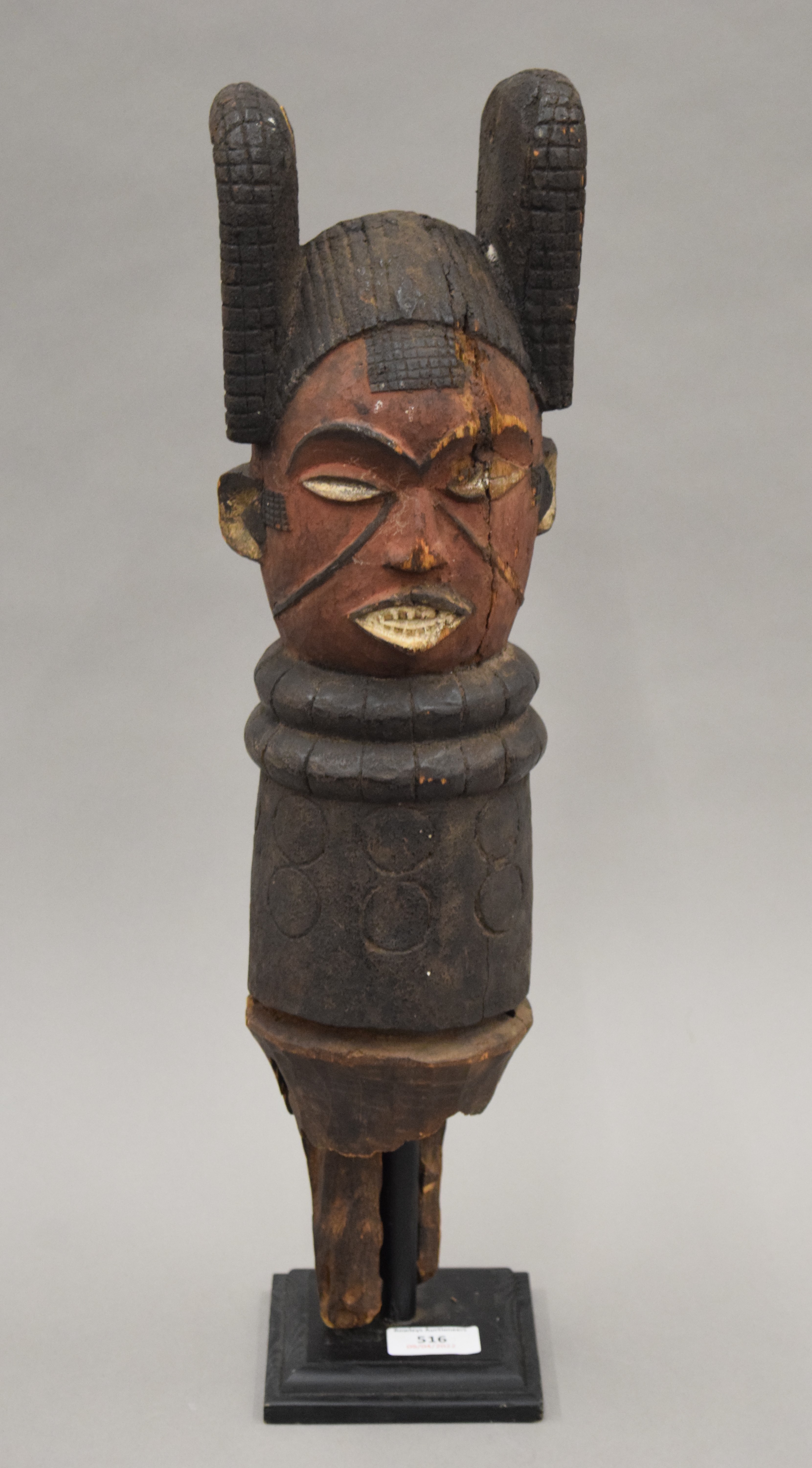 An African painted carved wooden tribal post, mounted on a display stand. 54 cm high overall.