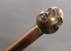 A walking stick with a four faced buddha form handle. 91.5 cm long.