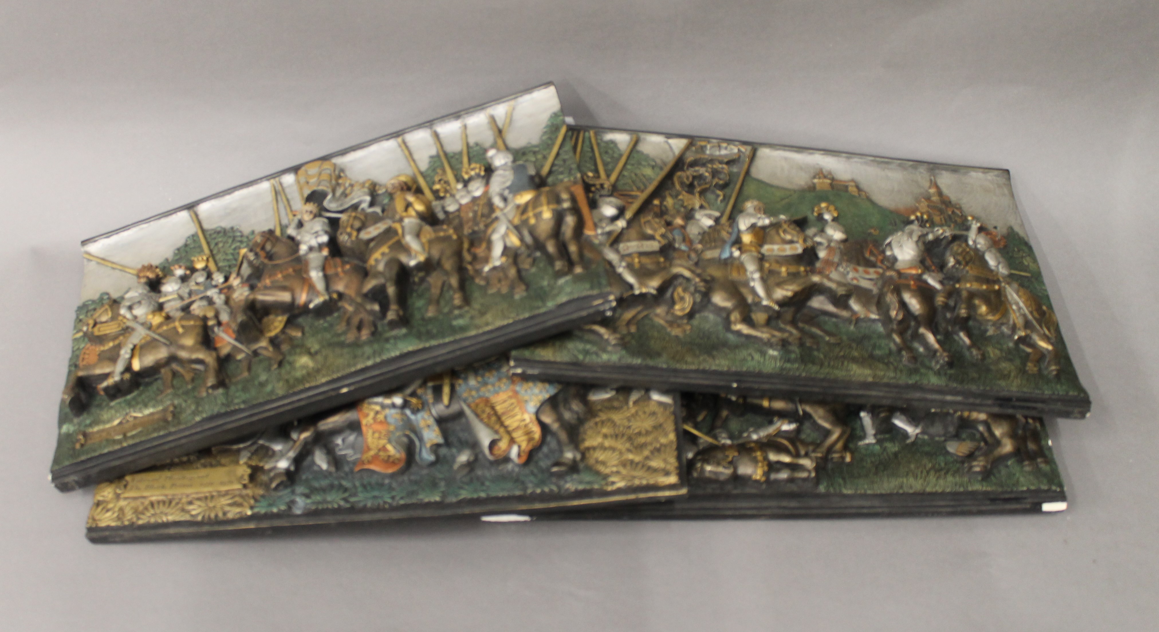Four plaques depicting battle scenes. Each approximately 40 cm wide.