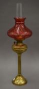 A Victorian brass oil lamp with ruby glass shade. 77 cm high overall.