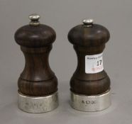 Two silver mounted wooden salt and pepper grinders. The largest 10 cm high.