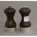 Two silver mounted wooden salt and pepper grinders. The largest 10 cm high.