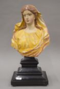 An 18th century polychrome painted carved bust of a young lady mounted on an ebonised plinth base.