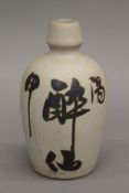 A Japanese sake bottle decorated with hand painted calligraphy. 16.5 cm high.