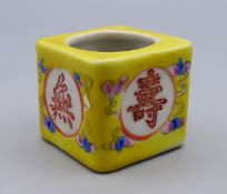 A Chinese porcelain yellow cube form ink pot. 3 cm high, 3.5 cm wide.