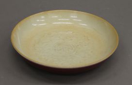 A Chinese porcelain dish with red ground exterior. 18.25 cm diameter.