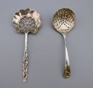 A silver straining spoon and a plated example. 12.25 cm long and 11.5 cm long. The former 15.