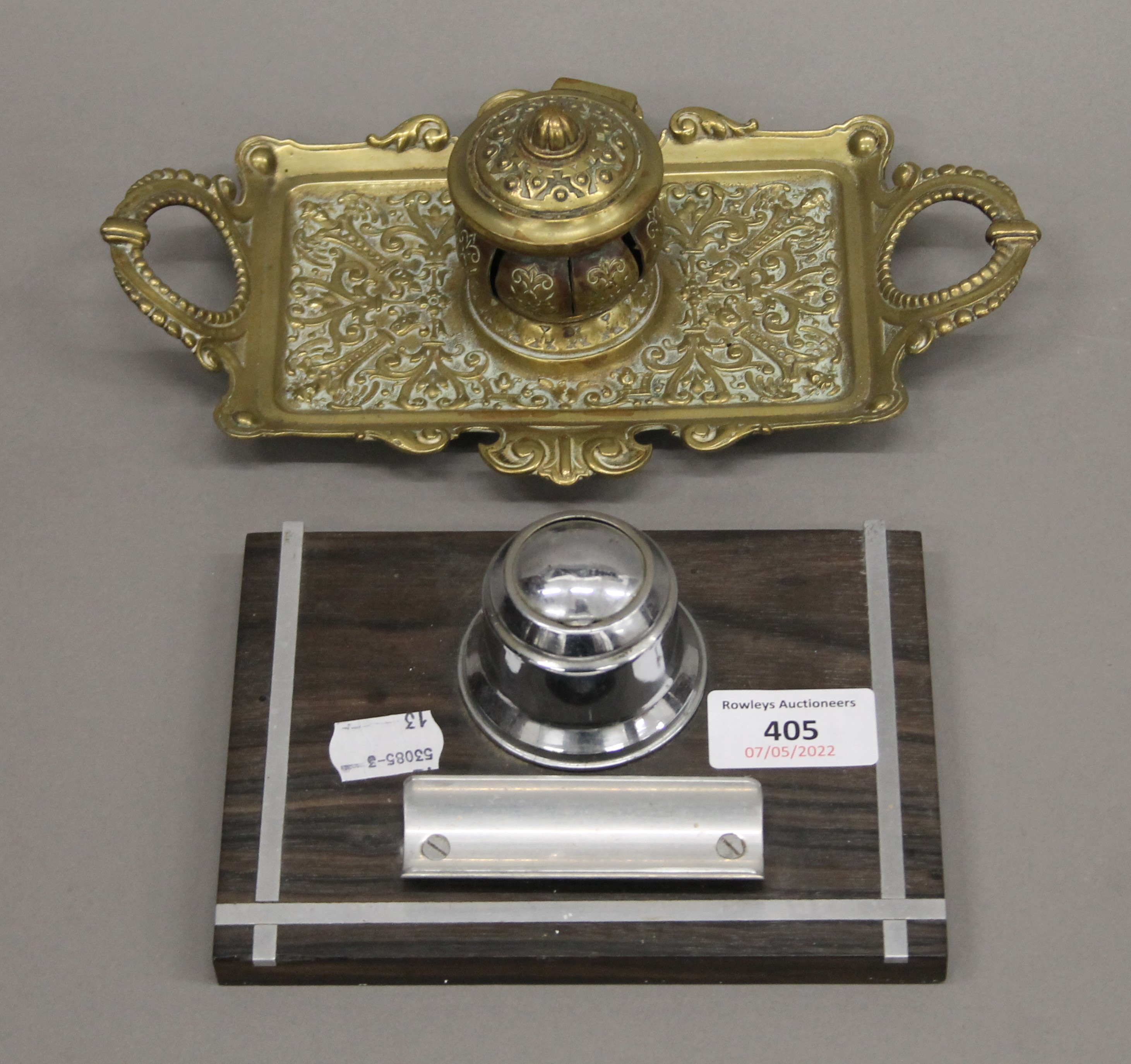 A brass inkwell and another inkwell. The former 23 cm wide.