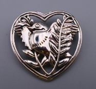 A silver brooch formed as a bird within a heart. 3.25 cm high.