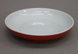 A Chinese shallow porcelain dish with copper red glaze exterior and white glaze interior,