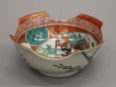 A small Japanese bowl hand painted with people to the interior and lotus flowers to the exterior,