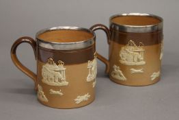 A pair of silver rimmed Doulton stoneware tankards. Each 8.5 cm high.