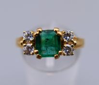 An 18 K gold, emerald and diamond ring. Ring size N.