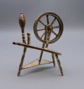 A silver model of a spinning wheel. 6 cm high.