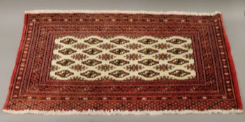 A small Afghan red ground rug. 106 cm x 55 cm.