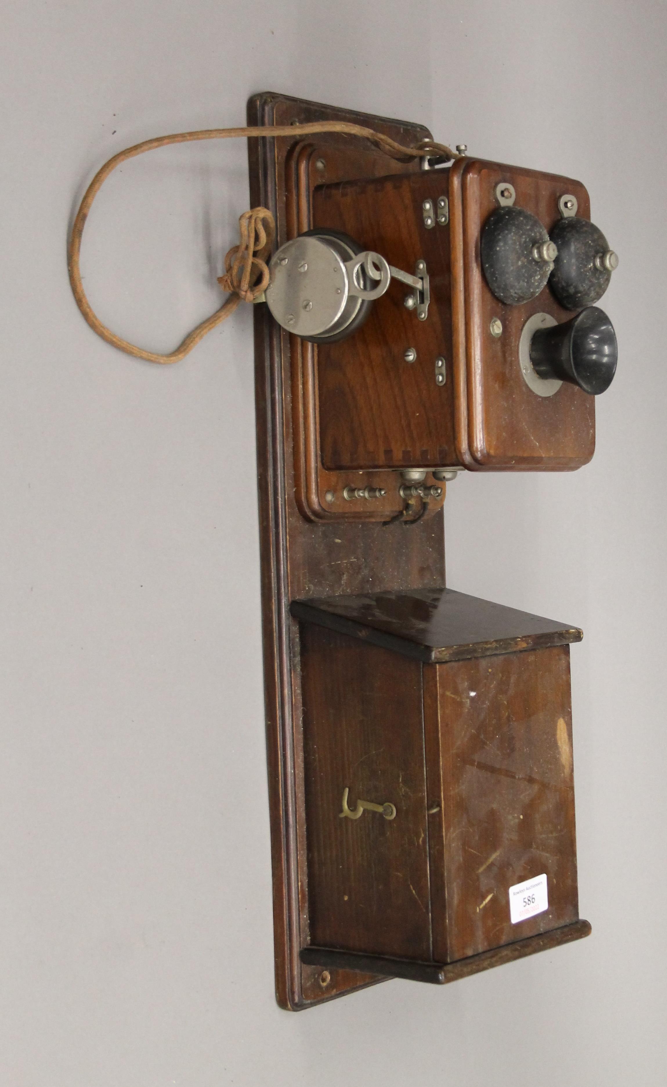 A vintage wooden wall mounted telephone.