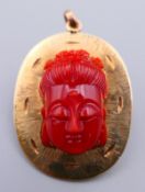 A 14 K gold pendant/brooch centred with a coral Buddha's head.