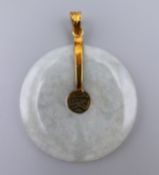 A 14 K gold mounted jade disc pendant. 3.5 cm diameter.