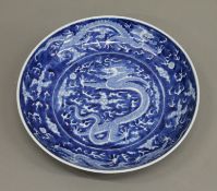 A Chinese porcelain blue and white dish decorated with dragons. 24 cm diameter.
