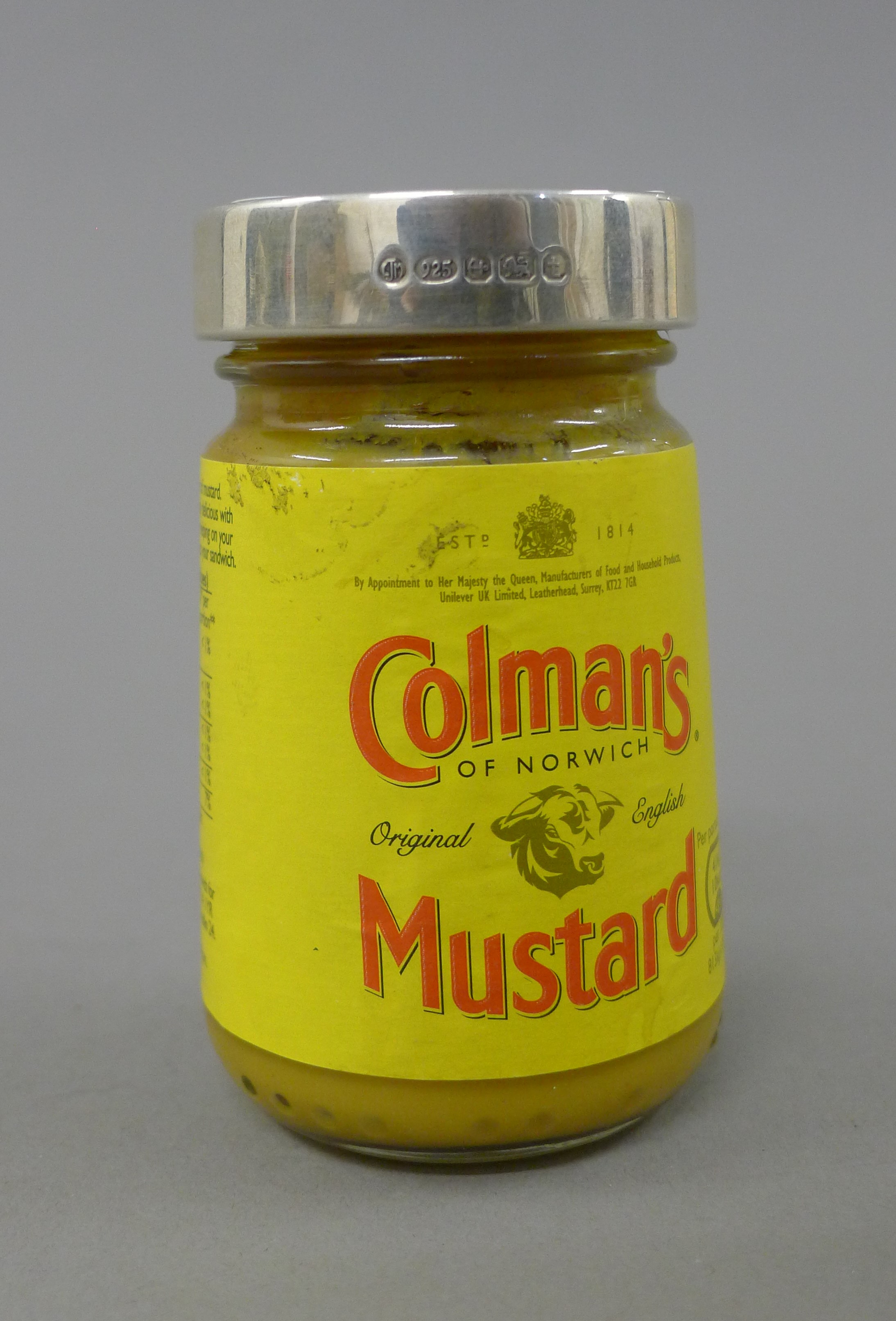 A silver lidded jar of Colman's Mustard.