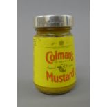 A silver lidded jar of Colman's Mustard.