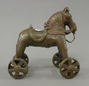 A brass horse on wheels. 18 cm long.