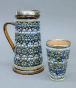 A Doulton Lambeth lemonade jug and beaker in the shell pattern. The former 23.5 cm high.