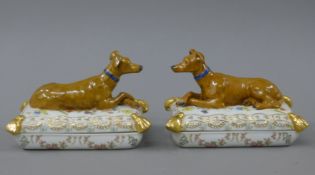 A pair of porcelain trinket boxes each formed as a dog on a cushion. 17.5 cm long.