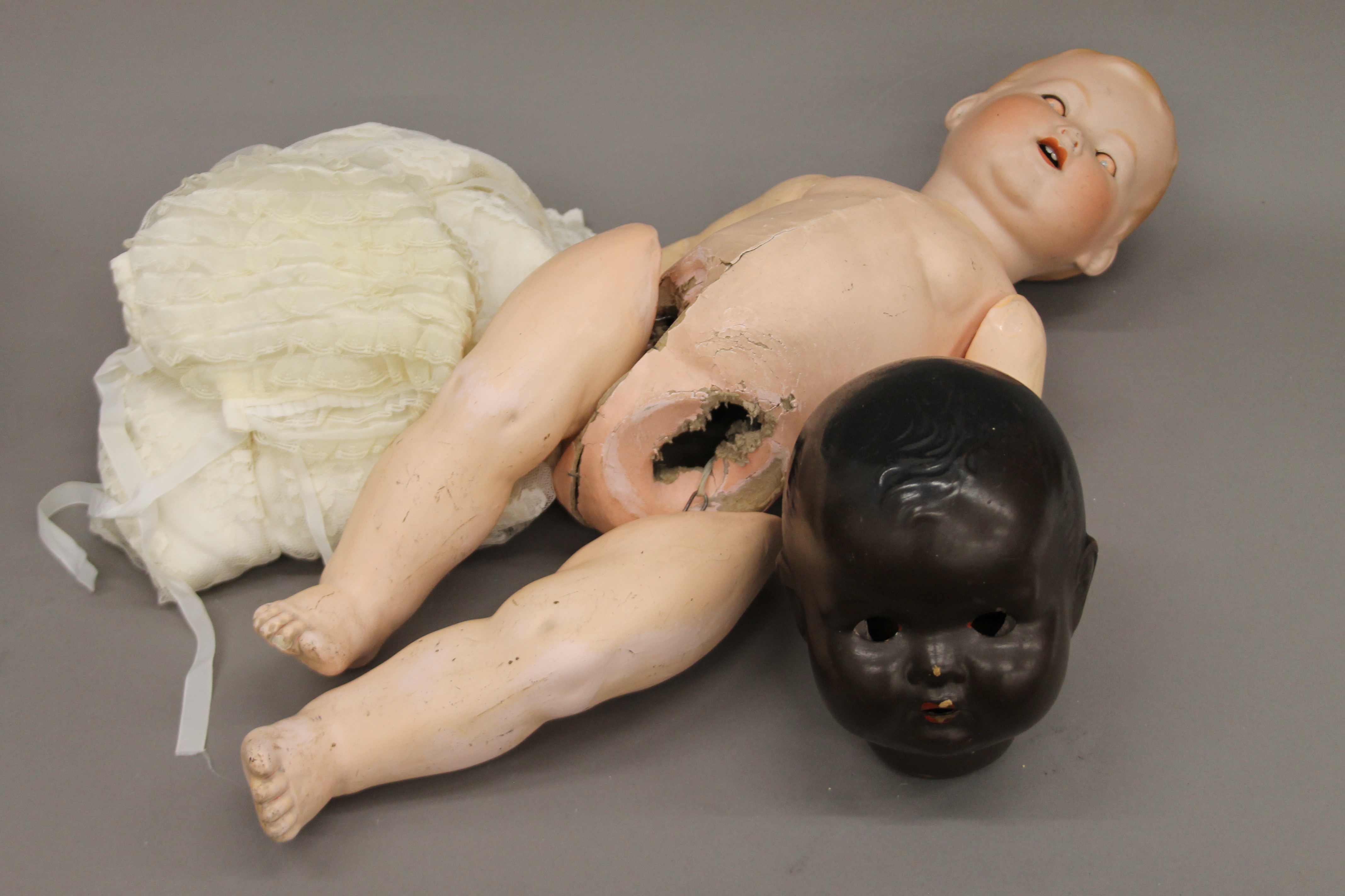 An Armand Marseille bisque headed doll, a lace Christening gown and another dolls head.