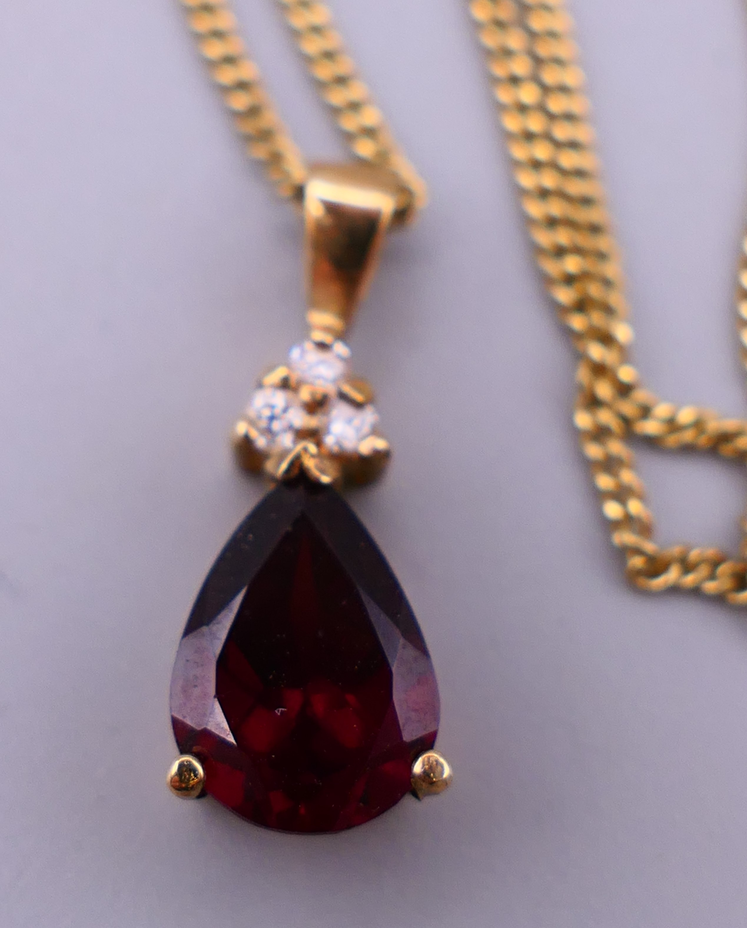 A 9 ct gold garnet pear drop pendant on a gold chain together with a pair of 9 ct gold earrings. - Image 4 of 6