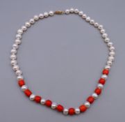 A string of pearl and coral beads with a 14 ct gold clasp. 41 cm long.