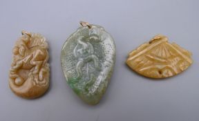 Three small gold mounted jade pendants. Largest 4.5 cm high.